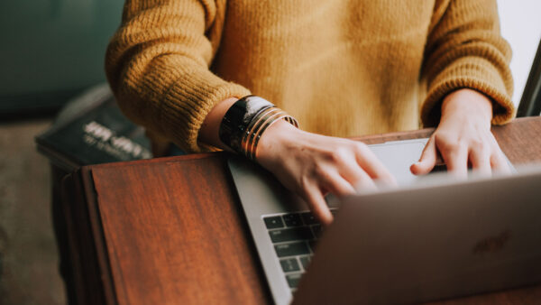 Person in yellow sweater working on laptop.