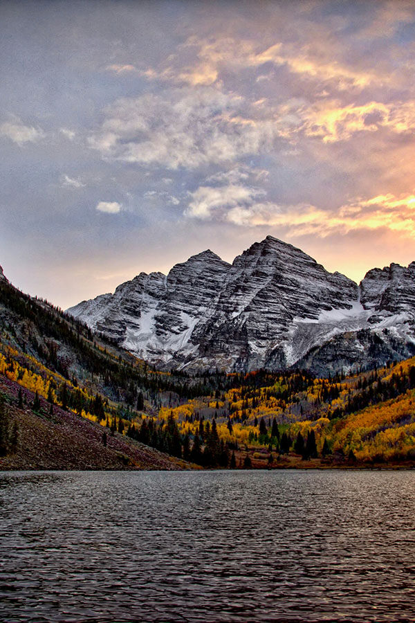 Maroon Bells mountains during autumn with snowcapped peaks and golden aspen trees.