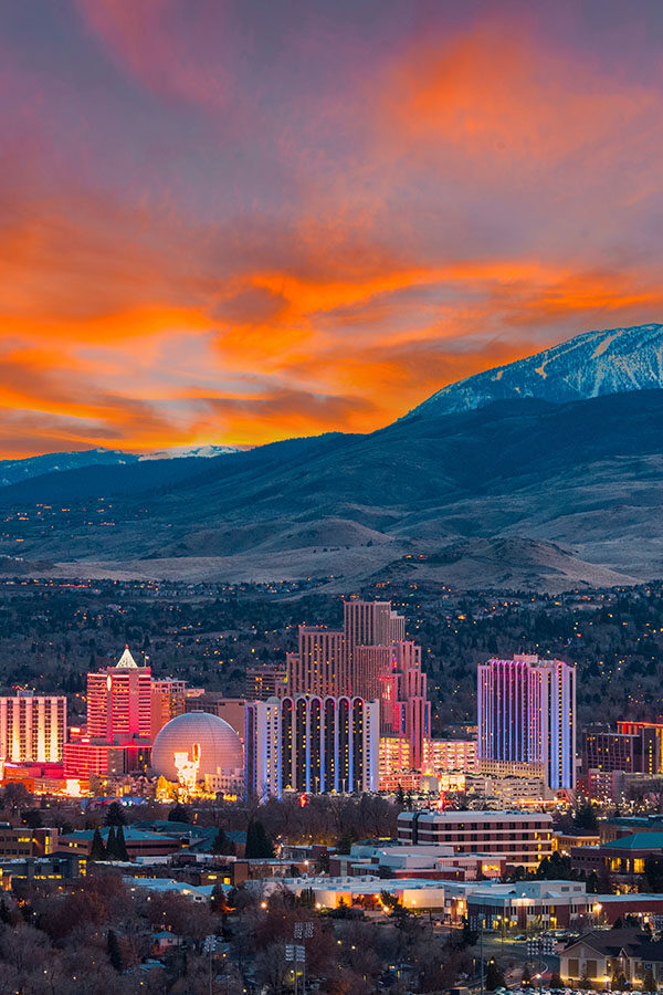 Reno Nevada skyline at dusk under cloudy purple and orange skies.