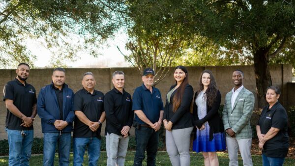 Oakmont employees posing together on grassy lawn in the sunshine.