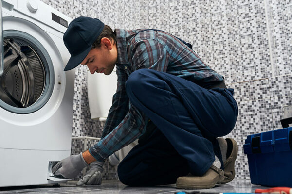 Maintenance worker repairing washing machine.